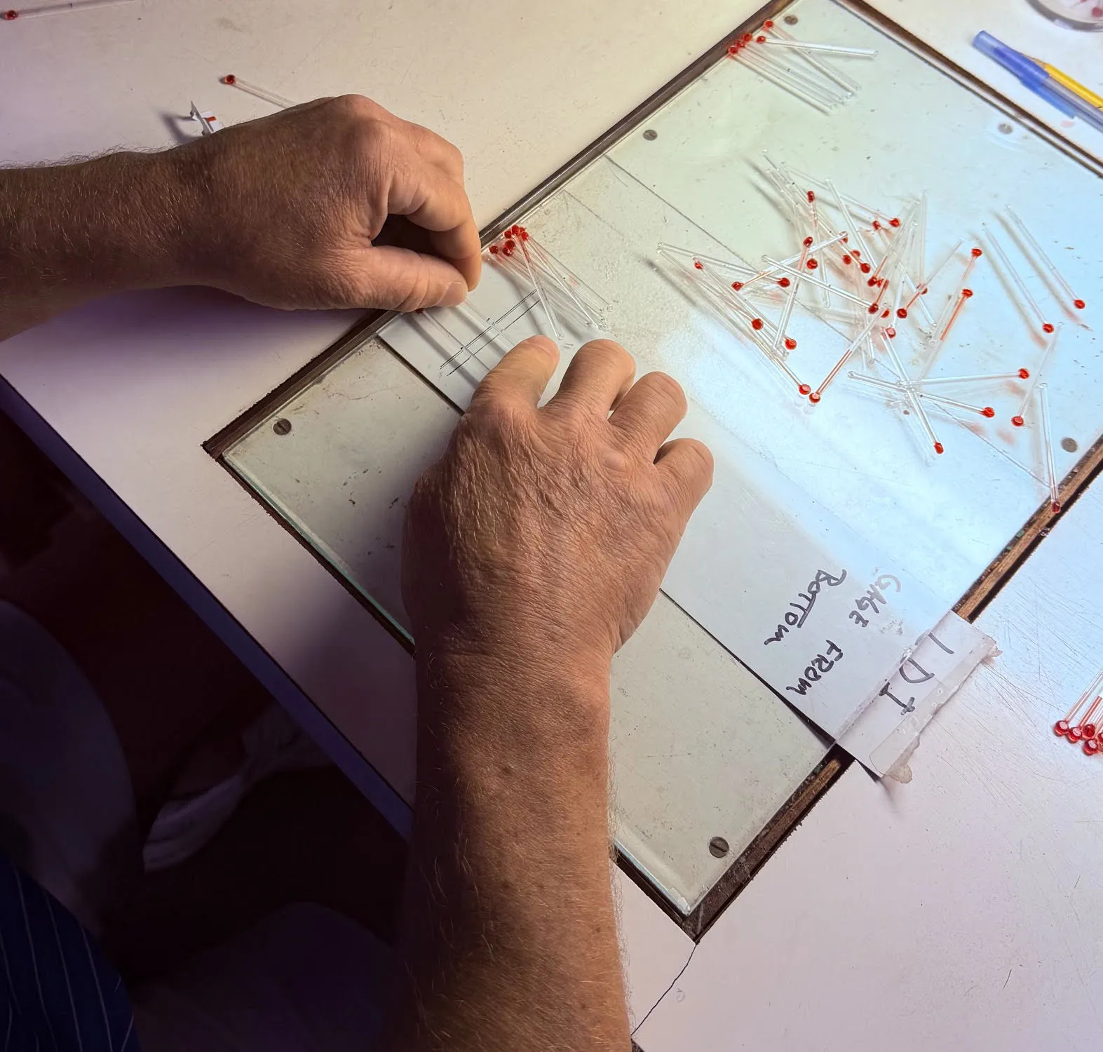 Echo Therm technician hand-aligning glass thermometer tubes on an illuminated light table, Springfield Ohio